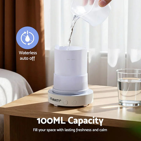 White essential oil diffuser with 100ml capacity on bedside table, water being poured in