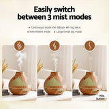 A wood grain essential oil diffuser displaying three adjustable mist modes on a white table.