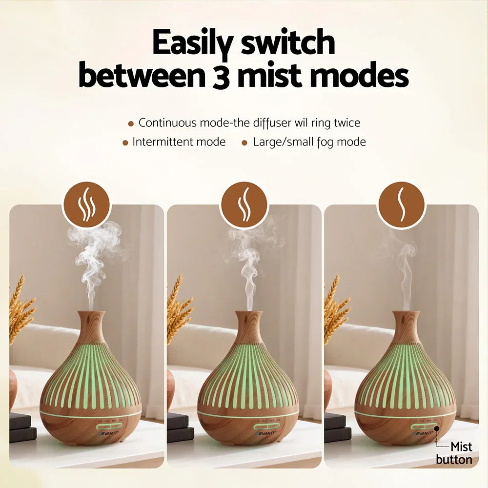 Wood grain essential oil diffuser with three mist modes, emitting vapor on a tabletop indoors.