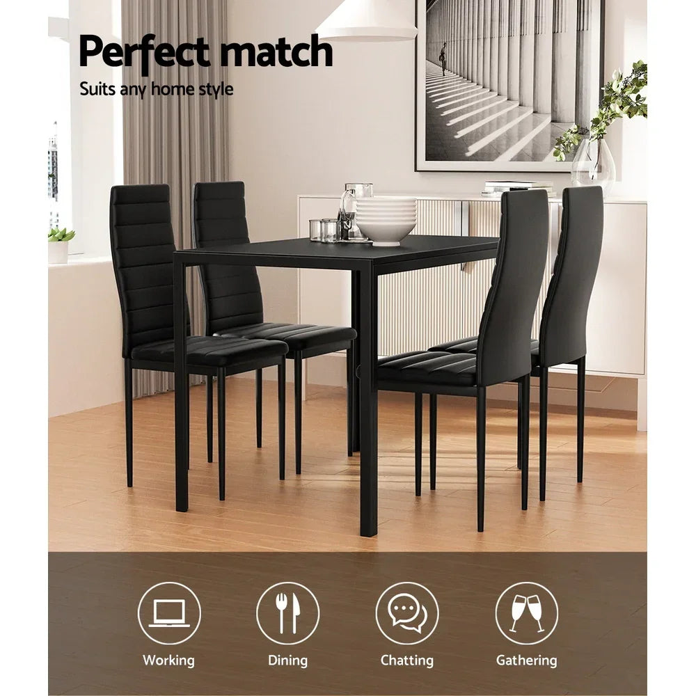 Modern black dining table set with four padded chairs in a bright, contemporary dining room.