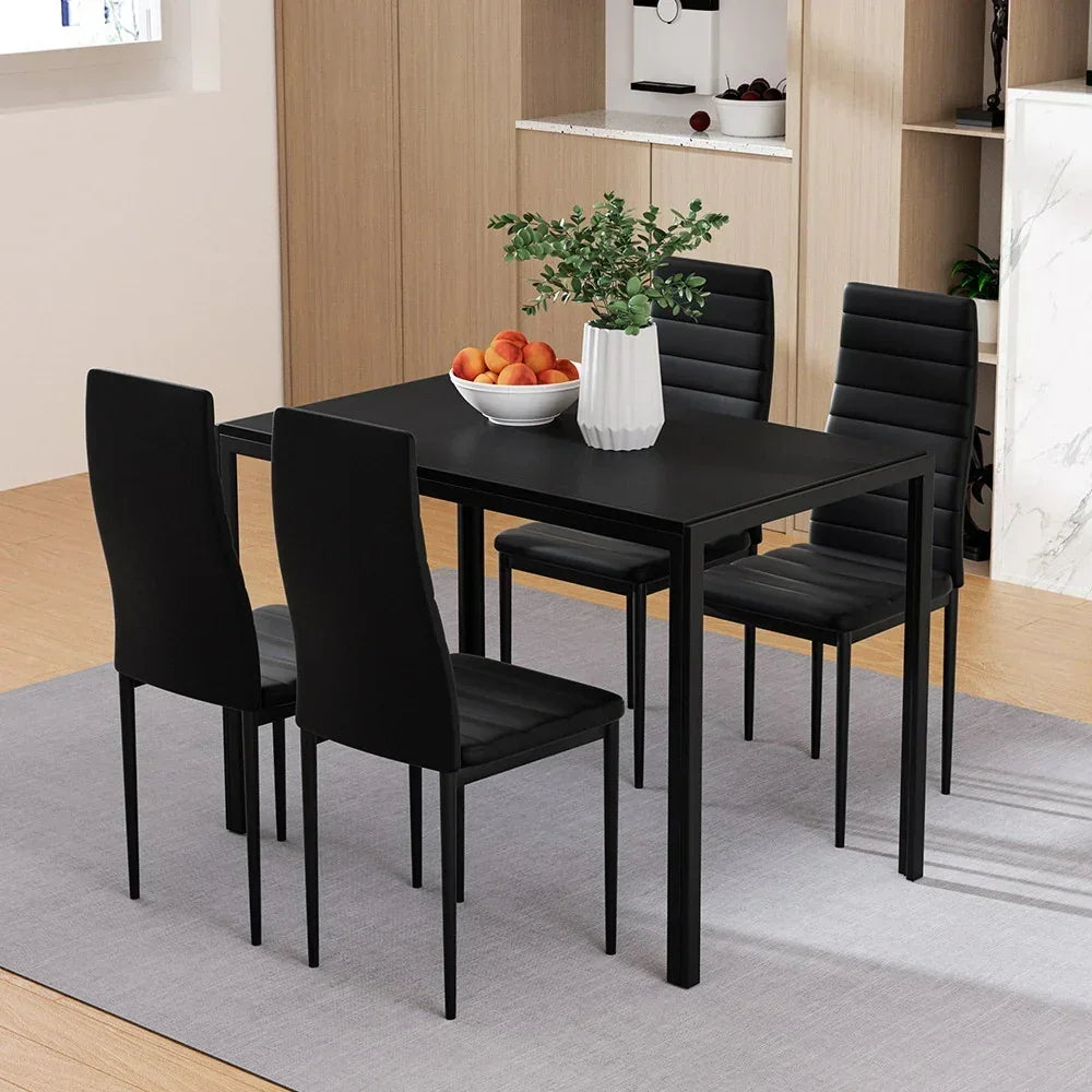 Modern black dining table set with four chairs, centerpiece vase and fruit bowl in kitchen