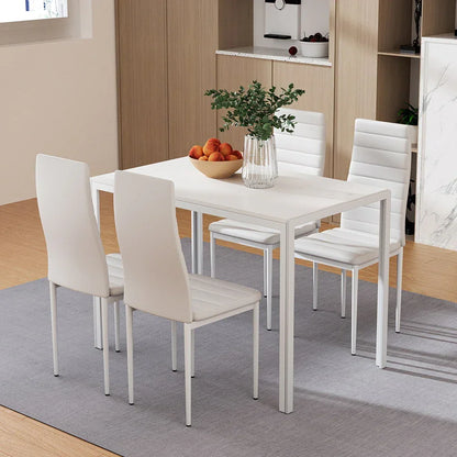 Modern white dining table with four chairs on gray rug, vase and fruit bowl in kitchen setting