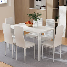 Modern white dining table with six chairs, fruit bowl, and vase in a contemporary kitchen
