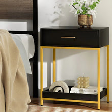 Modern black and gold bedside table with drawer, decorative vase, and decor accents