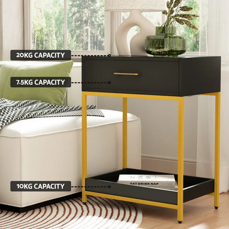Black and gold side table with drawer and shelf, labeled weight capacities, beside a sofa.