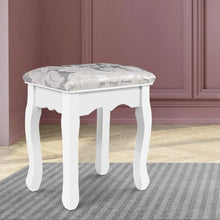 White wooden stool with ornate legs and a grey patterned upholstered seat on a rug