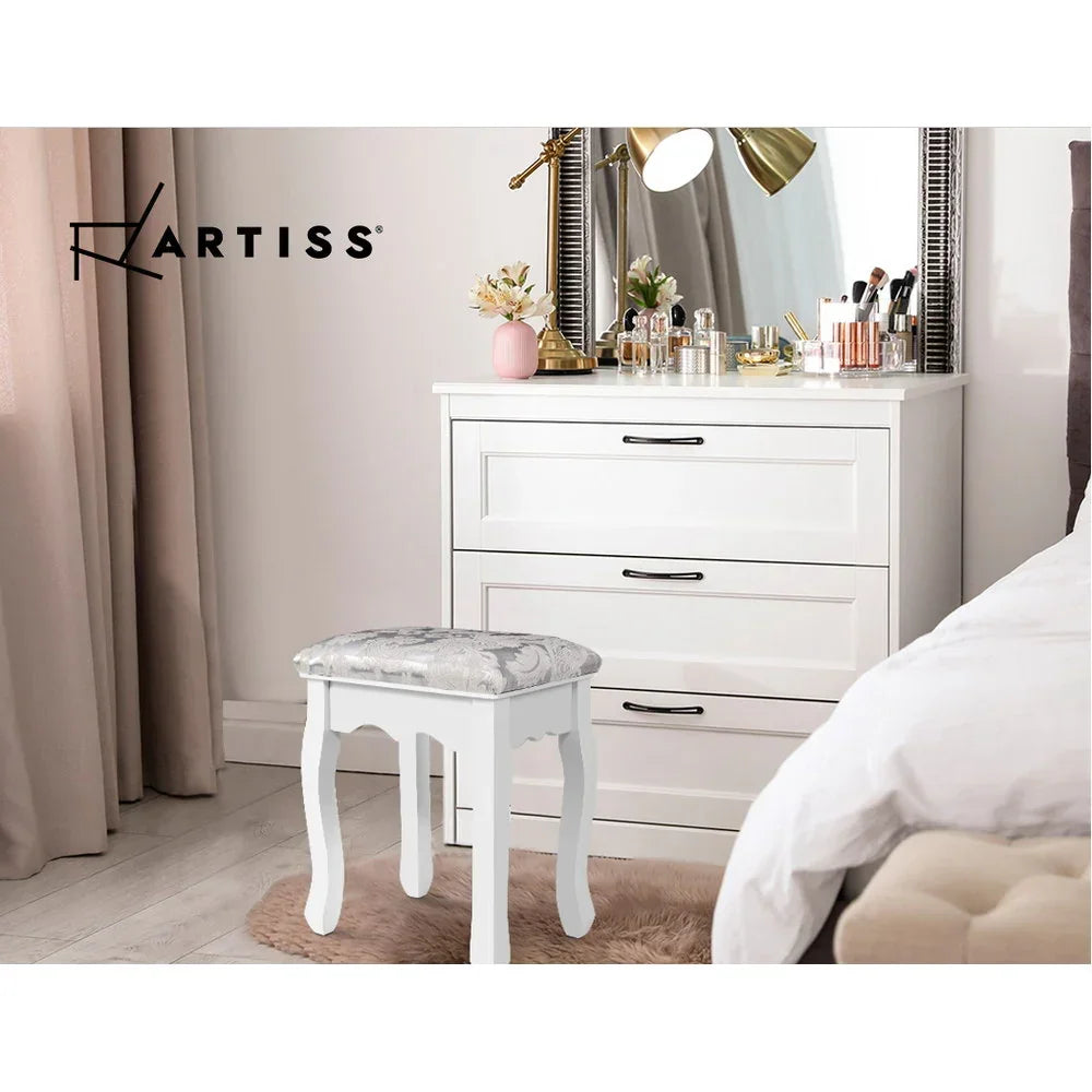 White vanity stool with patterned cushion in a modern bedroom near a white dresser and mirror