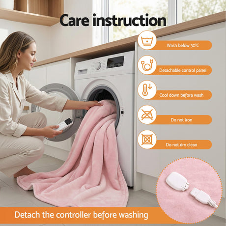 Woman loading pink heated throw blanket into washing machine, showing care instructions and detachable control panel.