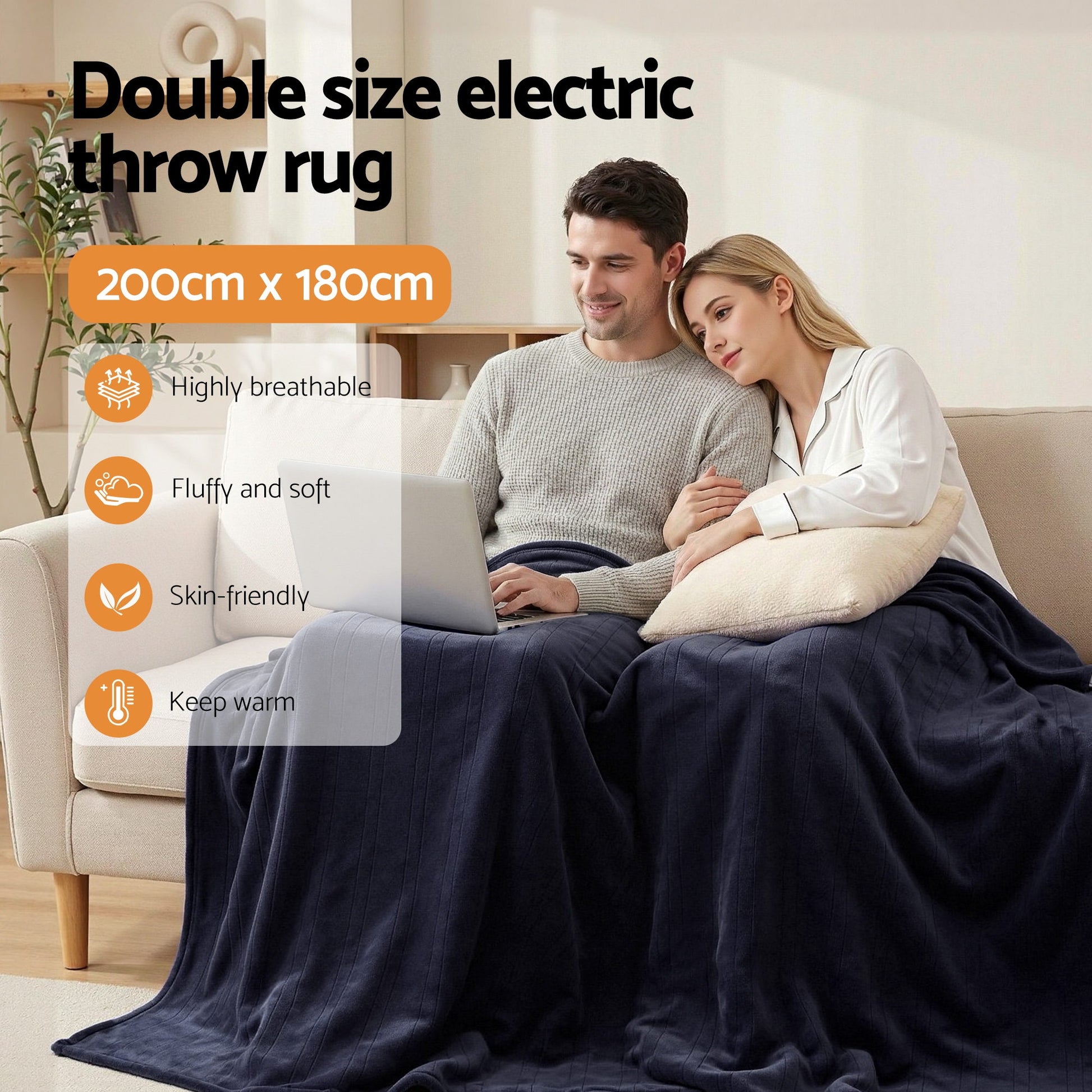 Couple on sofa using laptop, covered by navy double size electric throw rug, 200x180cm.
