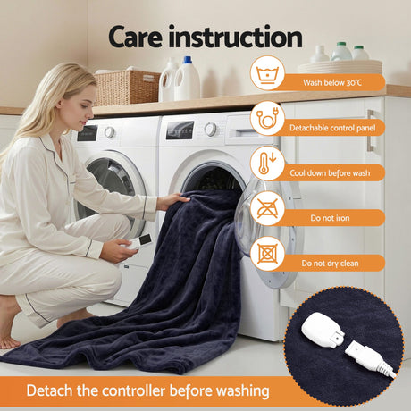 Woman placing dark plush heated electric throw rug in washing machine, care instruction icons visible.