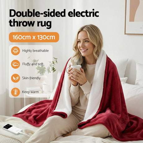 Woman sitting on bed with a red and white double-sided electric throw rug, holding a mug.