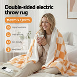 Woman on bed with orange and white checkered double-sided electric throw rug, holding mug