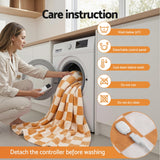 Woman removing detachable controller from orange checkered heated blanket before machine washing, laundry care instructions visible.