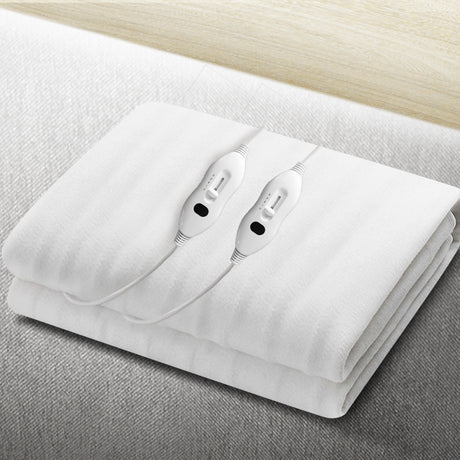White electric blanket with dual controllers on a light-colored bed surface