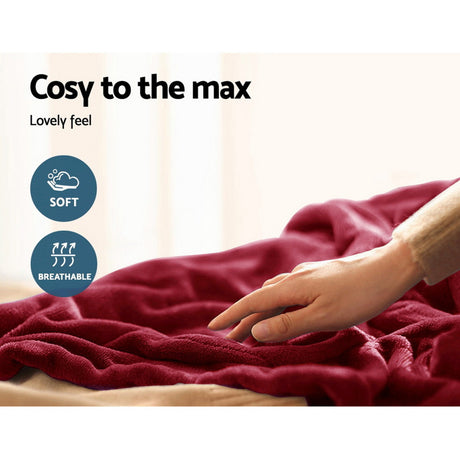 Hand touching a soft, burgundy throw rug with cosy, breathable texture on a bed.