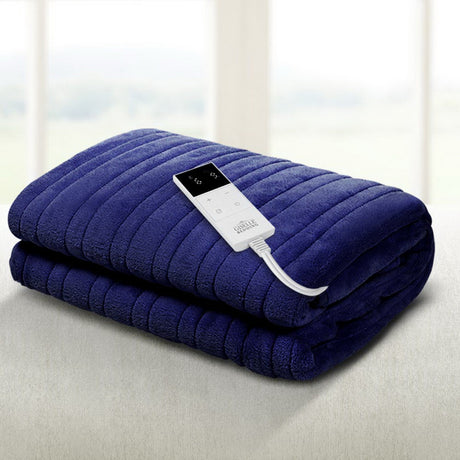 Folded navy blue electric heated throw blanket with remote control on bed.