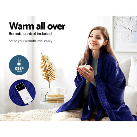 Woman using navy blue heated throw rug with remote control, sitting on a white couch