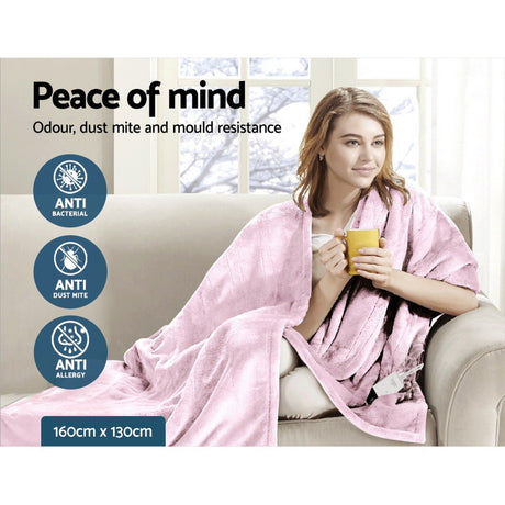 Woman sitting on a couch with a soft pink throw rug, holding a mug, highlighted anti-bacterial, anti-dust mite, and anti-allergy blanket, 160cm x 130cm size.