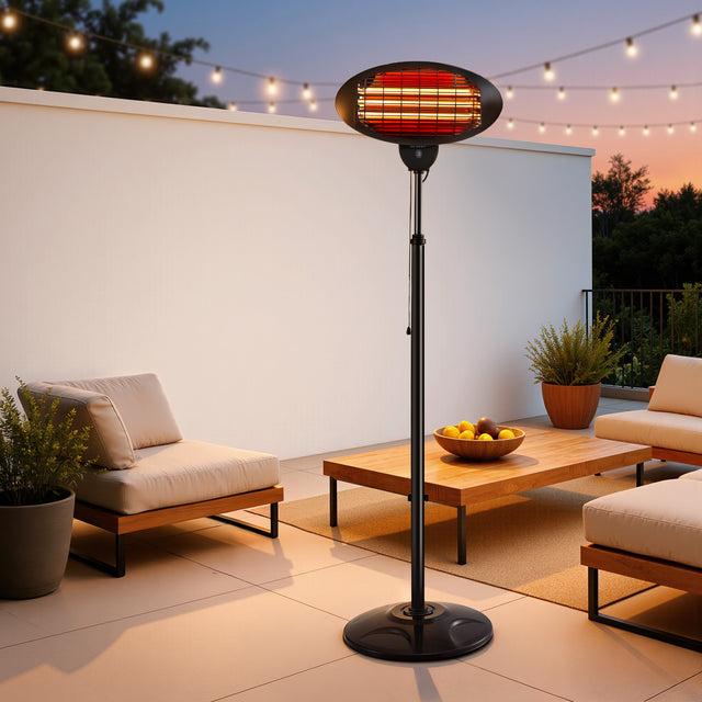 Outdoor patio heater with glowing element beside lounge chairs and wooden table at dusk