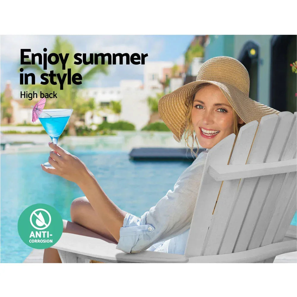 Woman relaxing on white high back outdoor chair by pool, holding blue cocktail, wearing sun hat