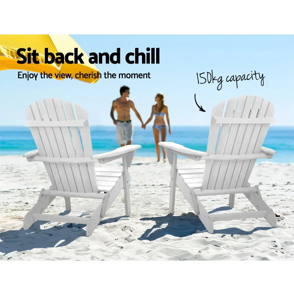 White Adirondack chairs on sandy beach with blue sea, yellow umbrella, and couple in swimwear.