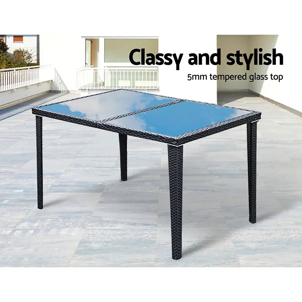 Outdoor dining table with black rattan frame and 5mm tempered glass top on patio