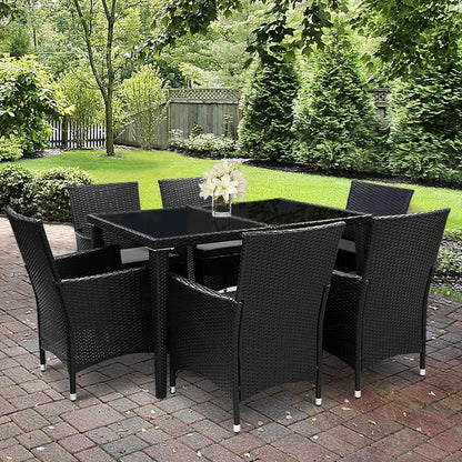 Outdoor black wicker dining set with glass table and six chairs on brick patio