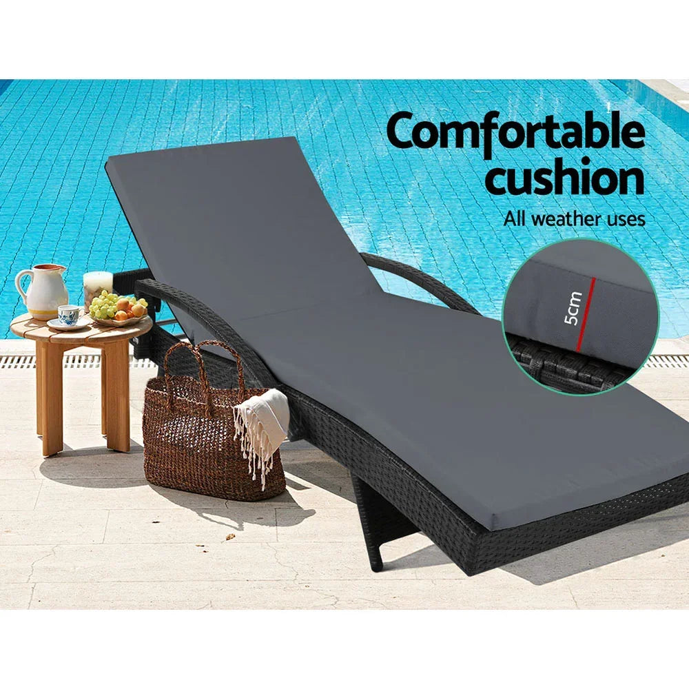 Outdoor lounge chair with thick grey cushion by a pool, side table with snacks and woven bag
