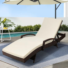 Outdoor rattan lounge chair with cream cushion by a pool on a patio rug
