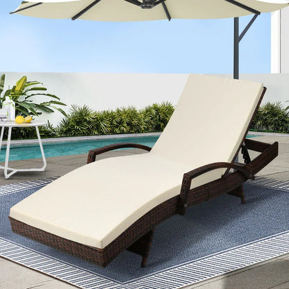 Outdoor rattan lounge chair with cream cushion by a pool on a patio rug