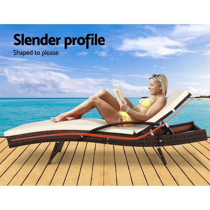 Outdoor rattan lounge chair with cushion on deck by the ocean, woman reading in swimsuit