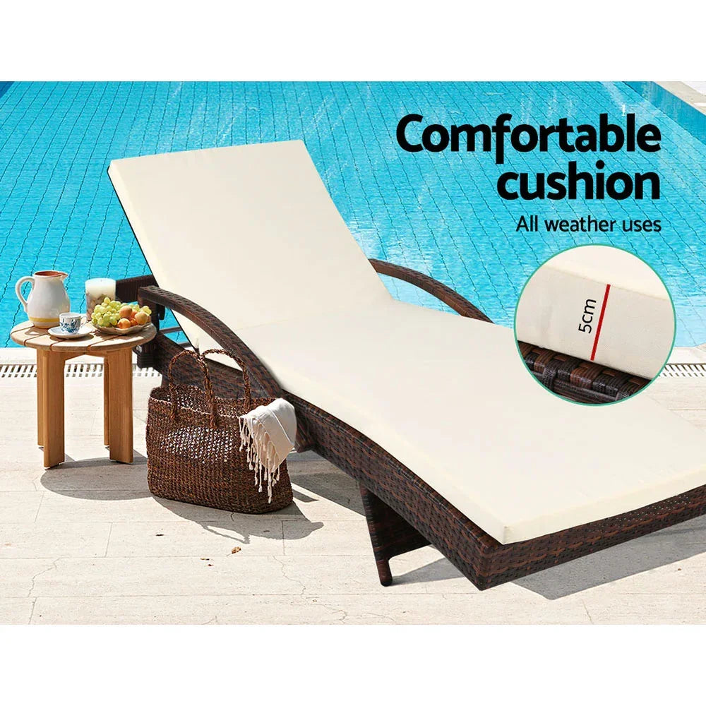 Brown wicker outdoor lounge chair with cream cushion by pool, food tray and woven bag nearby