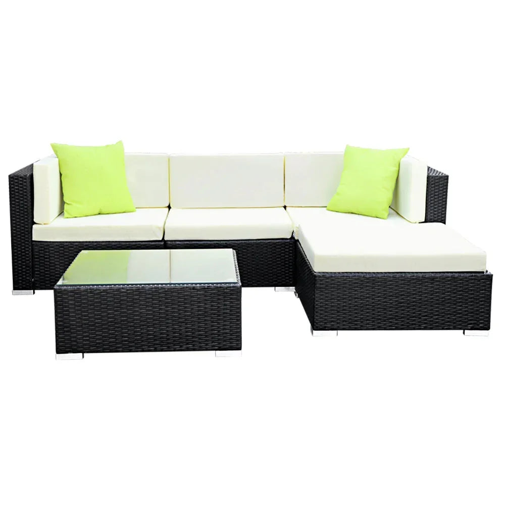 Black rattan outdoor sectional sofa set with cream cushions, lime green pillows, and glass table.