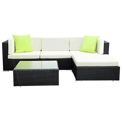 Black rattan outdoor sectional sofa set with cream cushions, lime green pillows, and glass table.