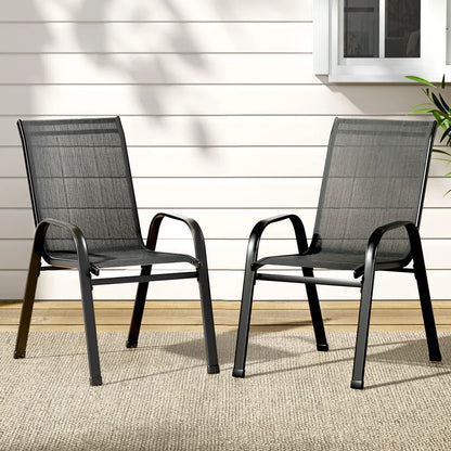 Pair of black outdoor mesh chairs on patio with light wall and window in background