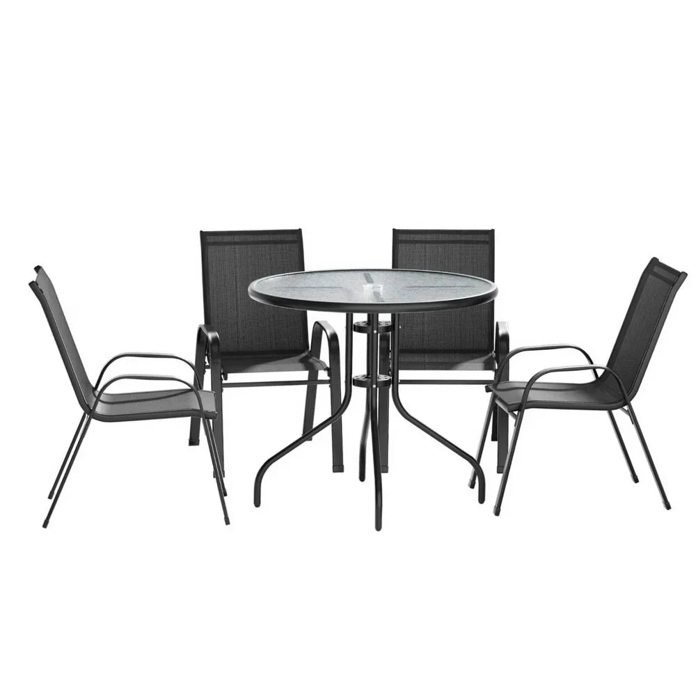 Black outdoor dining set with round glass table and four mesh chairs, modern patio furniture.