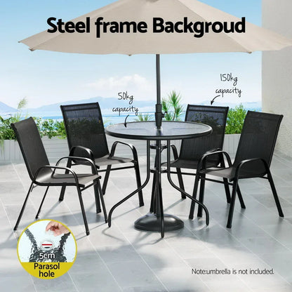 Outdoor black steel dining set with round glass table, four chairs, and beige patio umbrella.