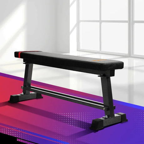 Flat weight bench with black padded surface and sturdy metal frame in a modern room