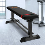 Flat weight bench with black padded surface and sturdy steel frame in a home gym setting