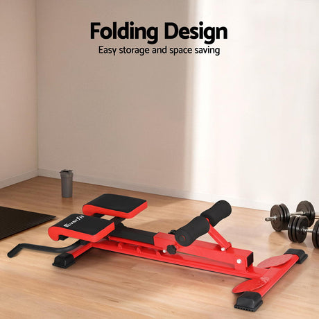 Red folding adjustable weight bench in a home gym setting with dumbbells and water bottle