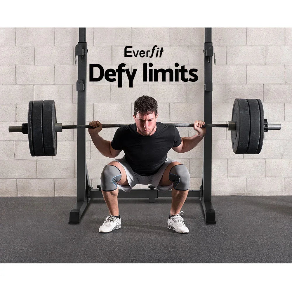 Man performing barbell squat on squat rack in gym with knee sleeves and weight plates
