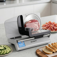 Electric meat slicer on kitchen counter with sliced bread, ham, and cucumbers