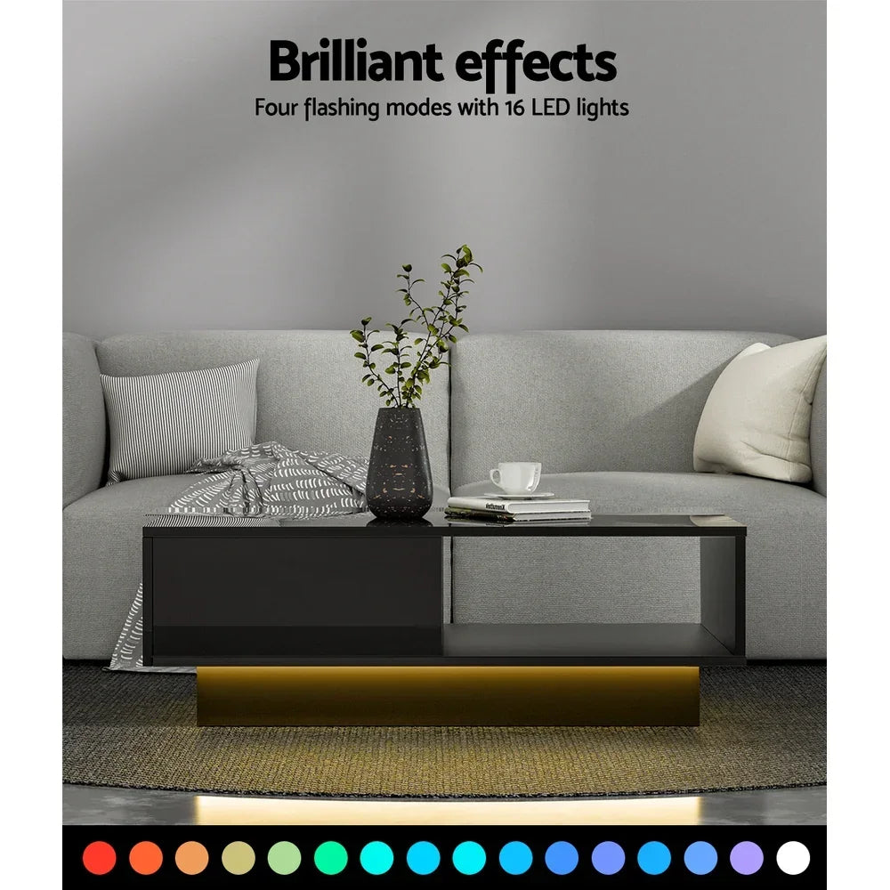Modern black coffee table with LED lights in living room, grey sofa, and decorative vase.