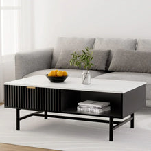Modern black and white coffee table with storage, bowl of oranges, and plant in bright living room