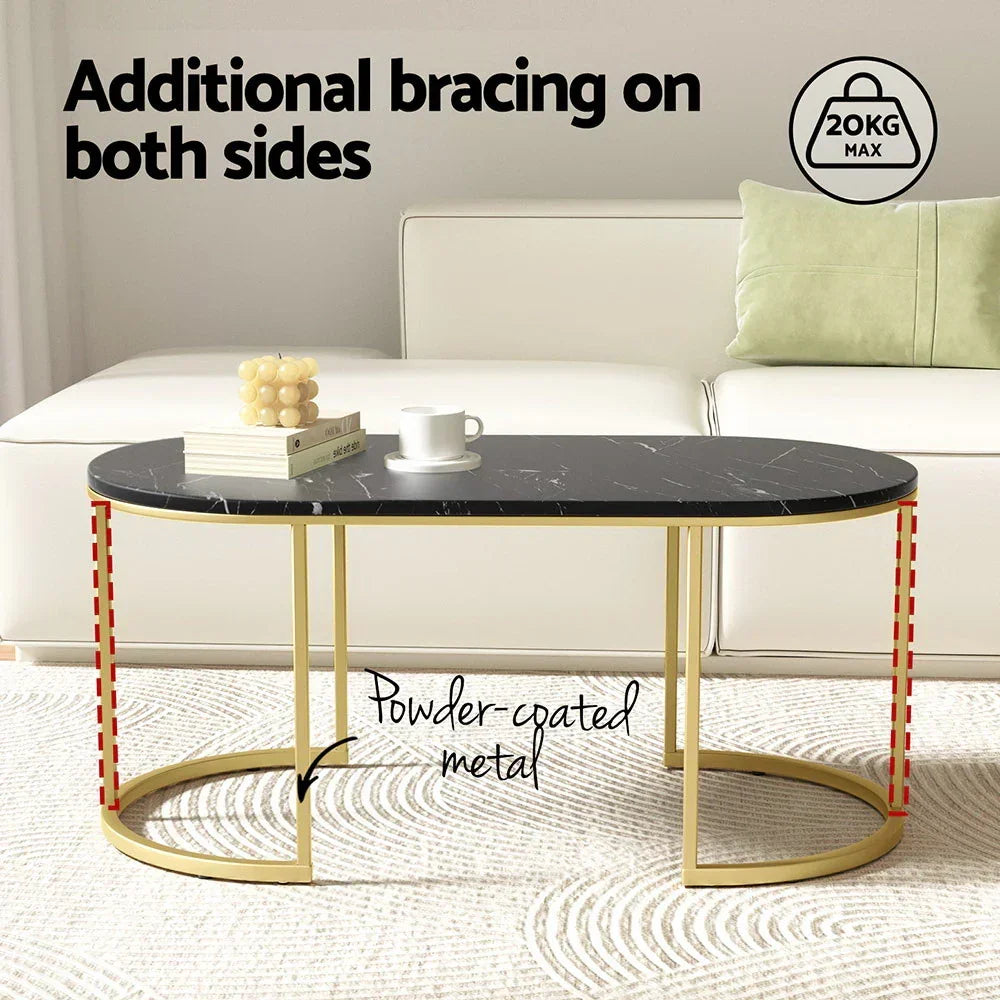 Oval black marble coffee table with gold powder-coated metal frame and sofa in background