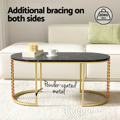 Oval black marble coffee table with gold powder-coated metal frame and sofa in background
