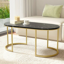 Modern black marble coffee table with gold metal legs in a bright living room