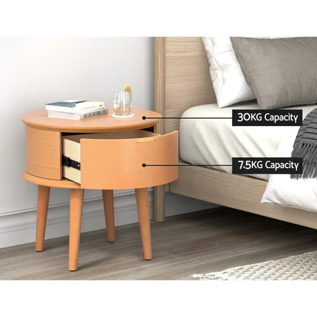 Round wooden bedside table with drawer, next to bed, showing 30kg and 7.5kg capacity.