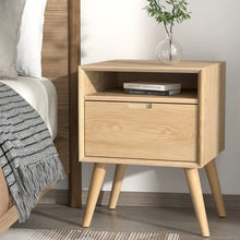 Light wood bedside table with drawer and open shelf, modern bedroom decor, books and vase on top