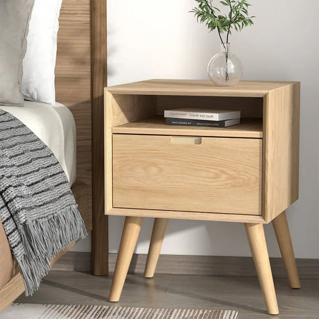 Light wood bedside table with drawer and open shelf, modern bedroom decor, books and vase on top